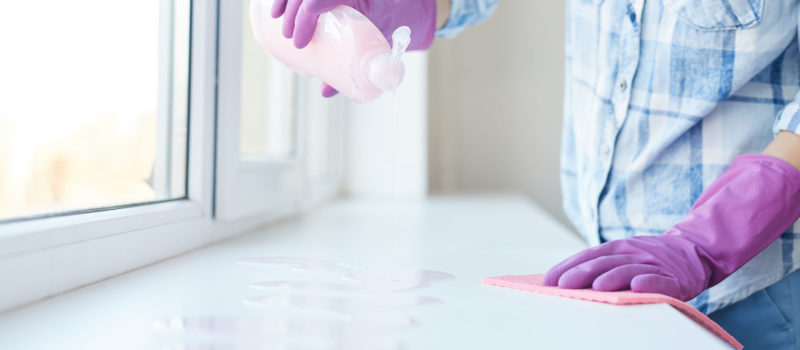 Cropped portrait of unrecognizable woman washing windows during Spring cleaning, focus on female hands wearing pink gloves, copy space